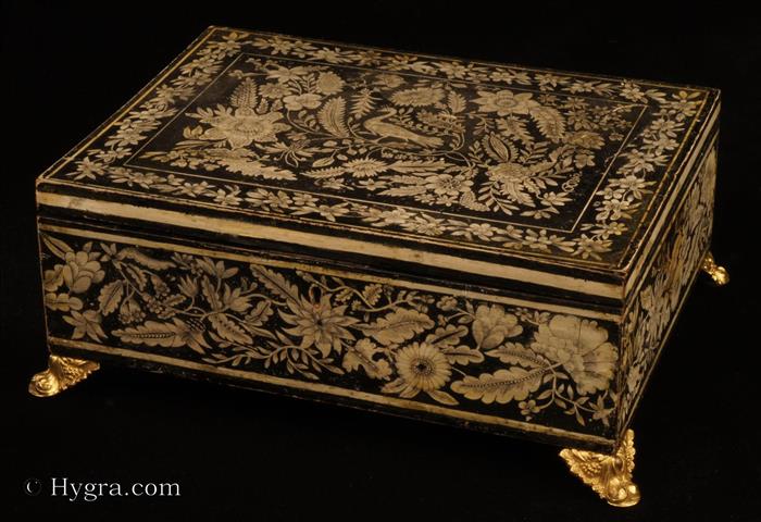 Penwork decorated  box made in gessoed beech and standing on embossed gilded brass feet. This particular box is very reminiscent of Anglo Indian work, both in the contrast of black on white which resembles ivory incised decoration. The patterns of plants and flowers are executed in the manner of fabric and embroidery design, which was fashionable in penwork of the period. However the top design goes further than most such work, in that the peacock is central to an asymmetrical tree of life motif which is characteristic of 18th century Indian inlaid work. Exceptionally well designed and executed.  Circa 1790.  Enlarge Picture